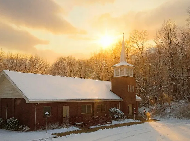 The church steeple and snowy roof at sunset in winter